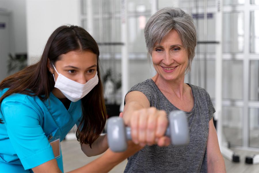 Medical professional assisting patient with a dumbbell